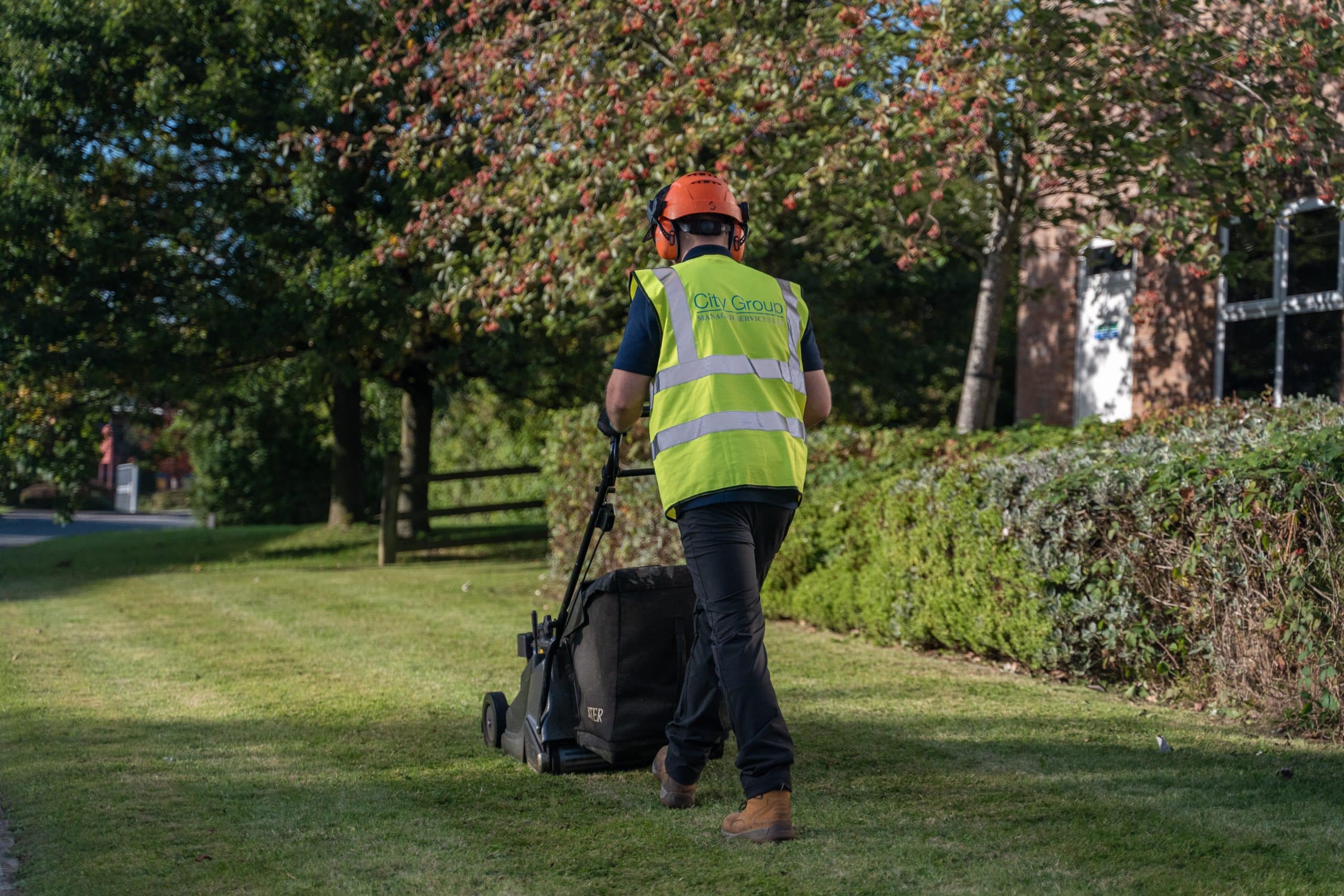 Man with City Group Hi-Vis Jacket mowing lawn